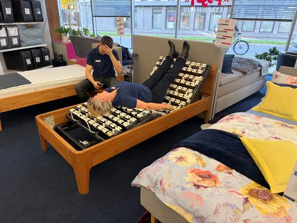 In einem Bettenfachgeschäft testet eine Person ein verstellbares Lattenrostbett.